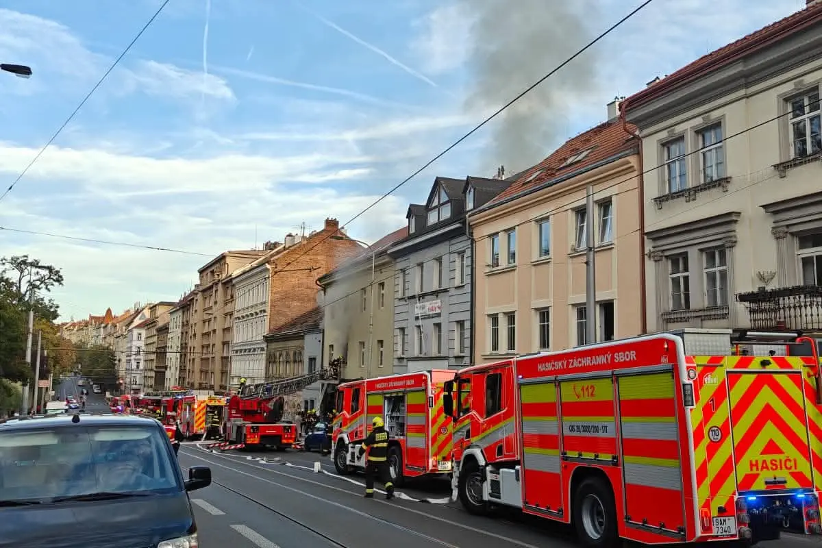 Z domu ve Francouzské ulici stoupá hustý kouř. Hasiči zachraňují lidi z oken