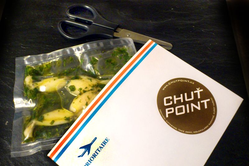 Pokrm „letecká zásilka z Francie“ sous vide žabí stehýnka vařená v bylinkovém pestu, podávané v letecké obálce par avion.