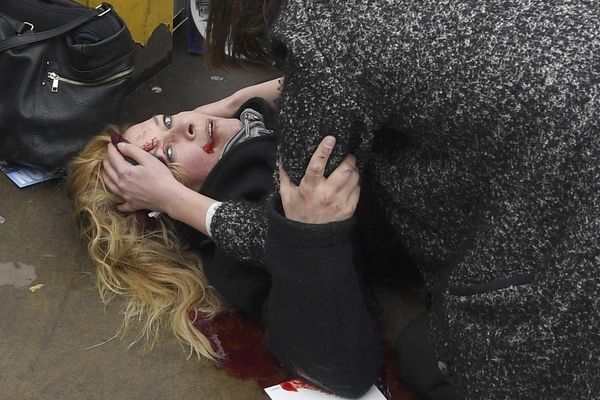 Kolemjdoucí pomáhají zraněné ženě na Westminsterském mostě.