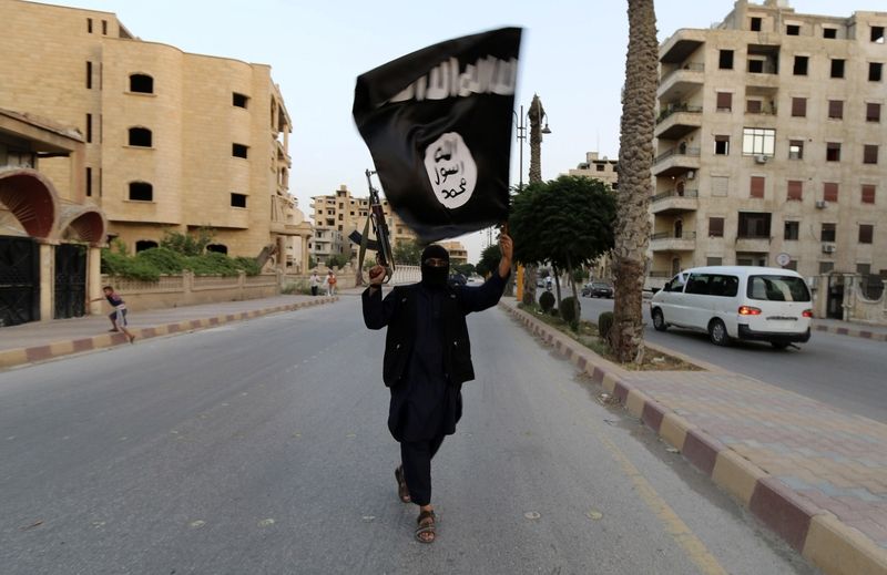 bojovník Islámského státu v Iráku a v Levantě s jeho vlajkou v syrské Rakce