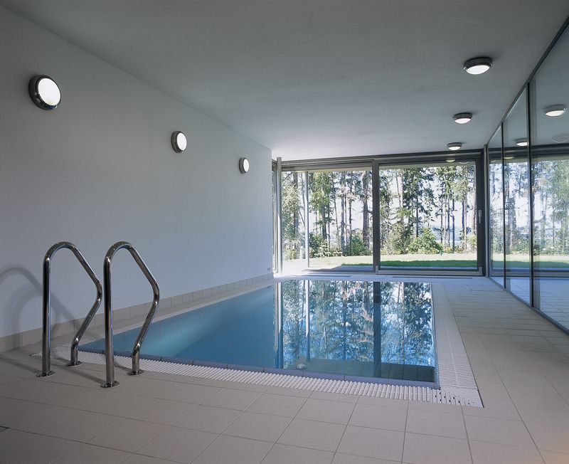 Bazén lemují dvě prosklené stěny, které jej oddělují od zahrady a sousední schodišťové haly. 