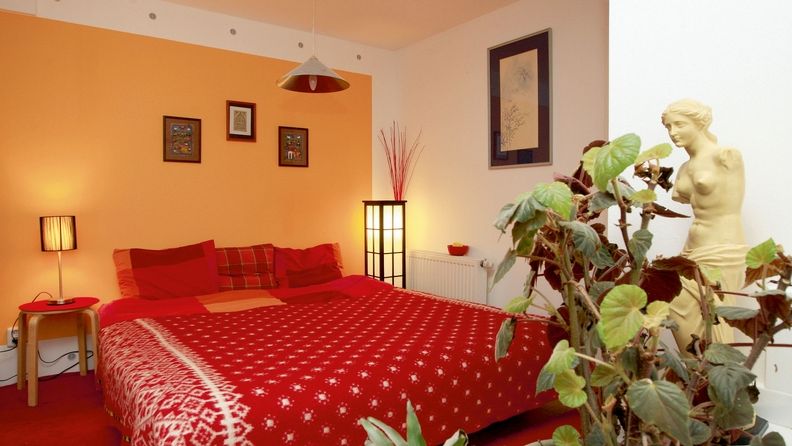 Největší část bytové plochy zabírá ložnice. Bílá a žlutá na stěnách s červenými doplňky prostor rozjasňují.
