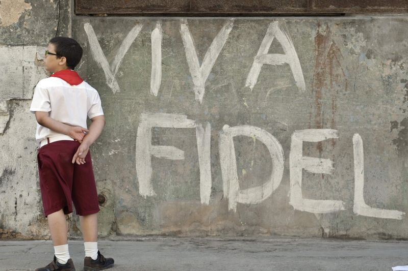 Kubánský školák postává vedle oslavného nápisu v jedné z ulic Havany.