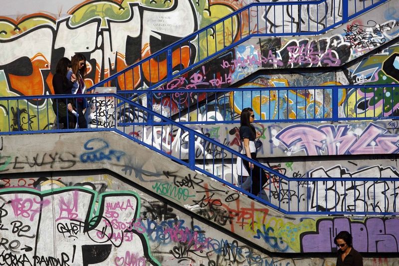 STŘEDA: Ženy scházející po schodech, jejichž stěny jsou zdobeny graffiti v srbském Bělehradě.