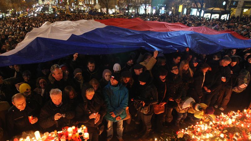 Lidé s českou vlajkou uctívají památku Václava Havla na Václavském náměstí.
