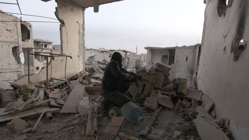 Syrský povstalec bojuje v troskách města