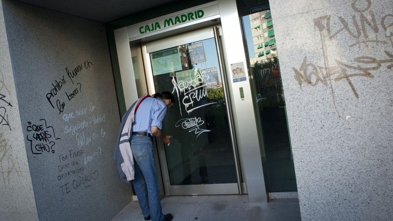 Muž v Madridu stojí před opuštěnou bývalou pobočkou banky Bankia. Ilustrační foto