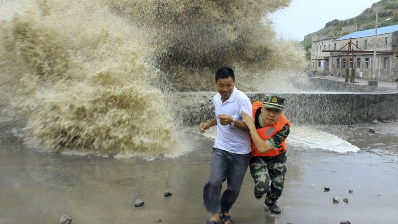 Voják pomáhá muži dostat se z dosahu vln rozbouřených tajfunem Soulik