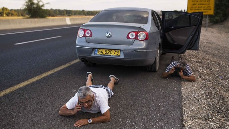 Izraelci po vyhlášení poplachu vyskákali z auta a kryjí se na zemi. 