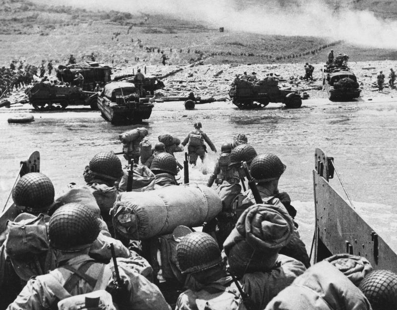 Američtí vojáci přistávají na pláži Omaha. Kouř na horizontu pochází z masivního dělostřeleckého bombardování, které vylodění předcházelo. Snímek z 6. června 1944