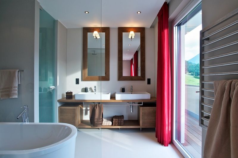 Koupelna je obložená velkoformátovou dlažbou Techlam od španělské značky Laventina o rozměru 1 x 3 m. Umyvadla jsou osazena bateriemi Hansgrohe a posazena na dubový nábytek zhotovený na míru. WC od koupelny oddělují dveře z pískovaného skla. 