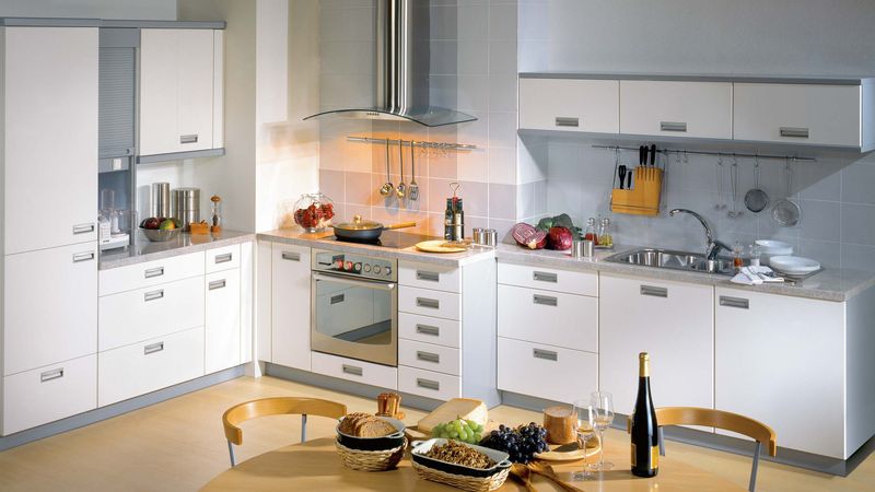 Kuchyně Forma uspořádaná do tvaru L účelně využívá členitost stěny. Barevnost šedé a bílé, jednoduché, hladké linie a dvířka se zahloubenými úchytkami dělají z místnosti příjemný prostor.

