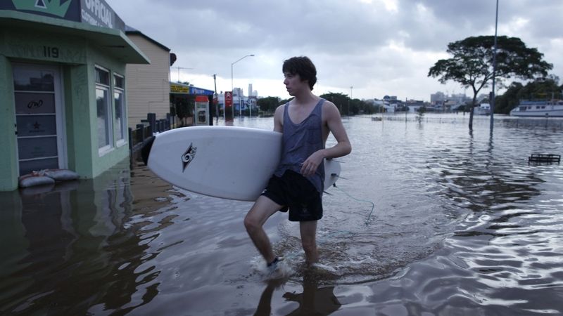Obyvatel Brisbane se surfem na zaplavené ulici