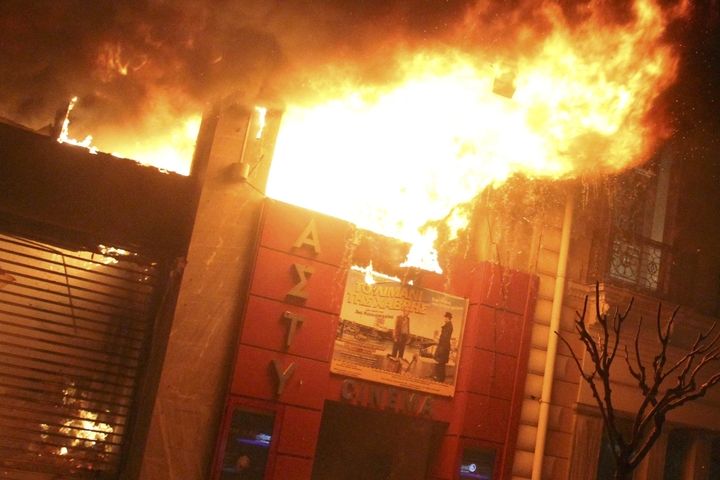 Hořící kino v centru Atén při protestech proti škrtům