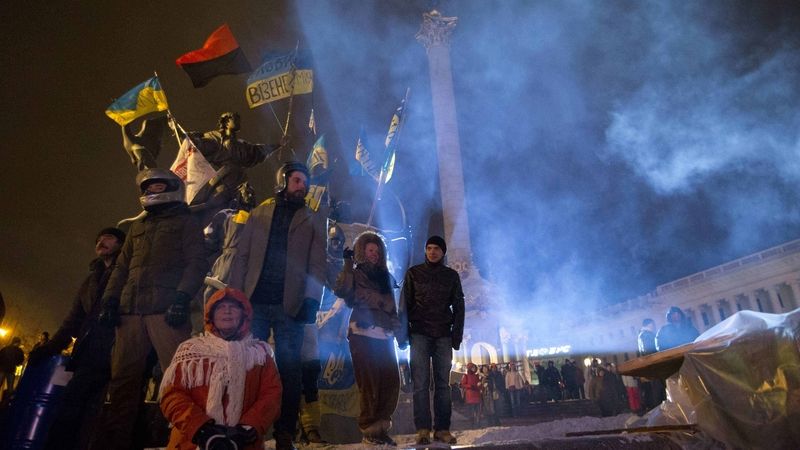 Demonstranti před památníkem na náměstí Nezávislosti vyzdobeným ukrajinskými a banderovskými prapory. 