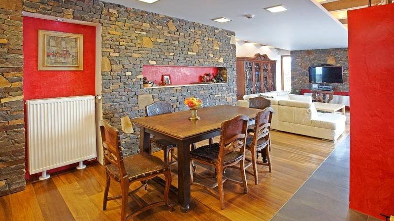 Ráz obývacího pokoje udává kamenné obložení obvodového zdiva, dekorativní niky jsou upraveny červeným benátským štukem. Keramická dlažba se stýká s plovoucí dřevěnou podlahou, která je určena pro méně zatížené plochy. 