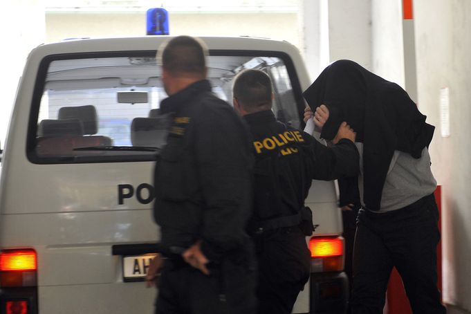 Policisté přivádějí na služebnu v Praze jednoho ze zadržených.