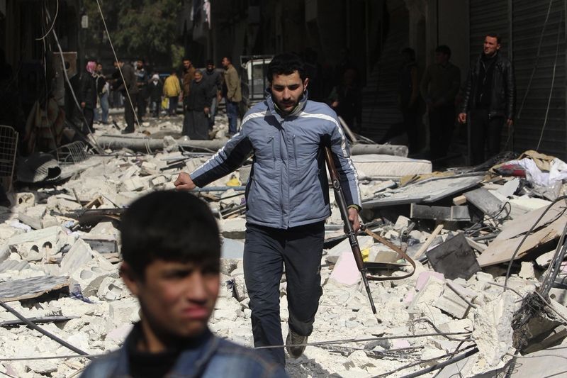 Bojovník Svobodné syrské armády v halabu na místě, kam dopadla raketa vypálená z letadla 