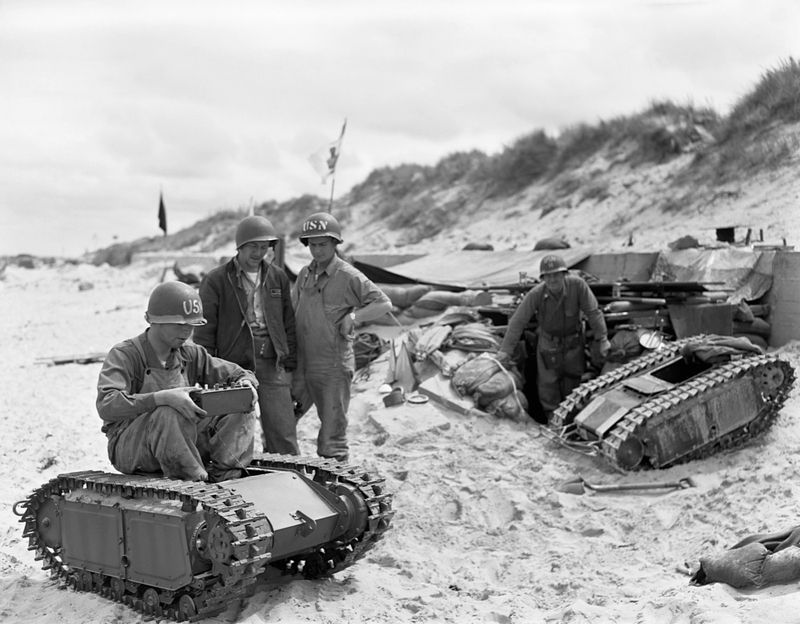 Američtí vojáci na pláži Utah s ukořistěnými německými minitanky, které spojenci nazývali brouk. Němci dálkově ovládané pásové transportéry používali k dopravení nálože za nepřátelskou linii.