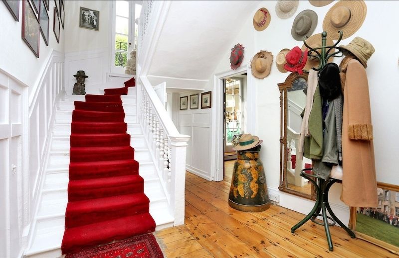 Všechna podlaží domu propojuje dřevěné schodiště v cukrově bílé barvě s výrazným červeným běhounem.