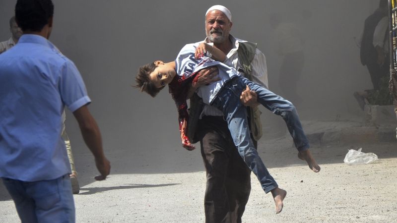 Muž v Damašku nese zraněného chlapce.