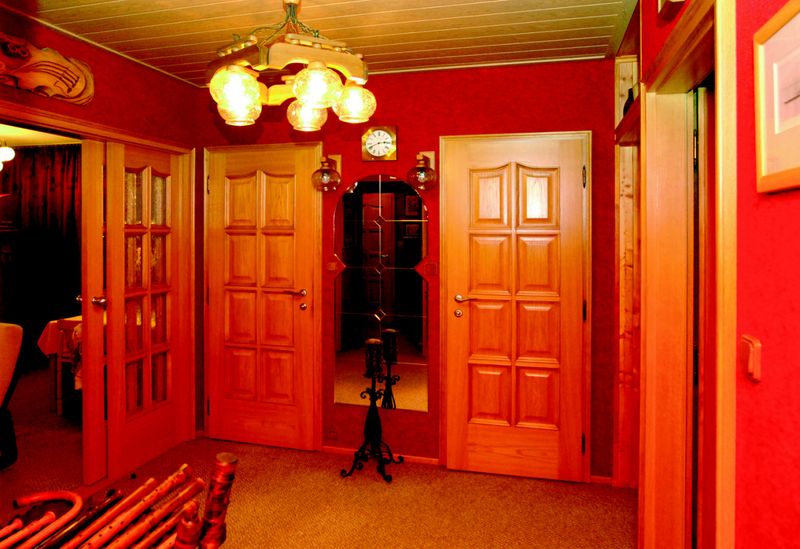 Oblíbené prvky z přírodního dřeva, včetně všech dveří, dotvářejí atmosféru precizně zařízeného bytu v panelovém domě. Vítejte v centru bytu (pohled z předsíně). Některé stěny pokrývá koberec.