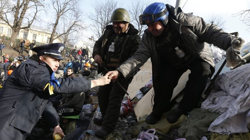 Demonstranti v Kyjevě se zdraví s policistou, který přešel do jejich řad.