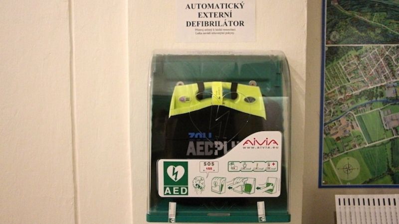 Automatický defibrilátor je umístěn na zdi naproti podatelny.