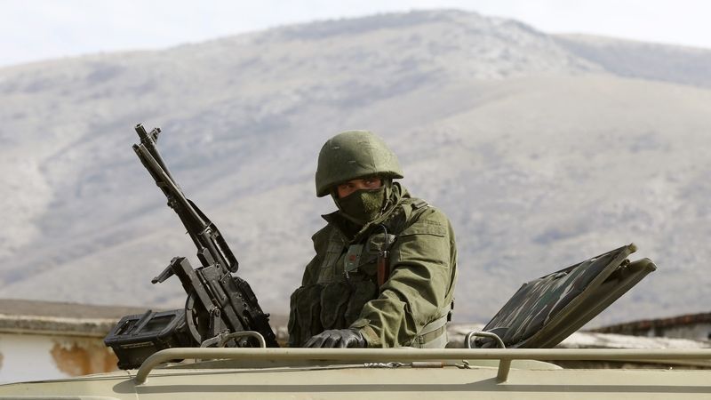 Voják v neoznačené uniformě střeží ukrajinskou základnu v Perevalném na Krymu 