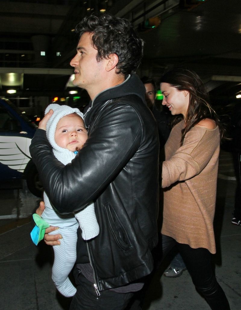 Pyšný tatínek Orlando Bloom se synem Flynnem v náručí, v pozadí Miranda Kerrová.