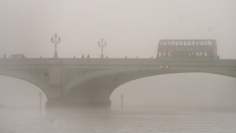 Červený dvoupatrový autobus, jeden ze symbolů v Londýna, v druhém symbolu Londýna - mlze.