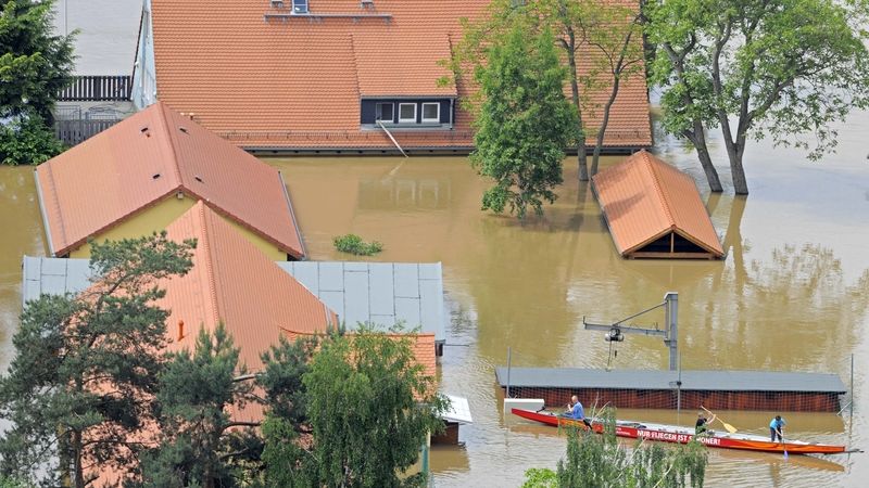 Lidé plují v člunu k domku zatopeném na předměstí Drážďan. 