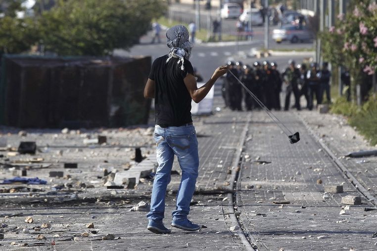 Palestinec hází kameny na izraelské policisty během demonstrací na jeruzalémském předměstí Šuafát obývaném převážně Araby.