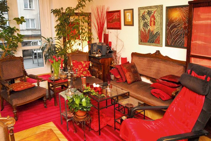 Útulný obývací pokoj se vstupem na terasu zdobí nejen hostitelčiny obrazy. Zde jsou dominantní tóny červené.