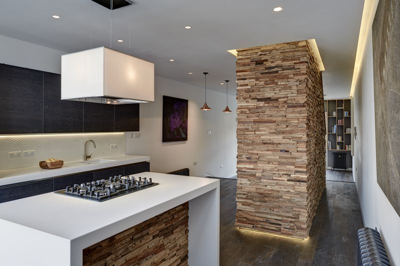 Tak, jak je dřevo využito na stěnách schodiště, objevuje se i na centrálním pracovním pultu v kuchyni.