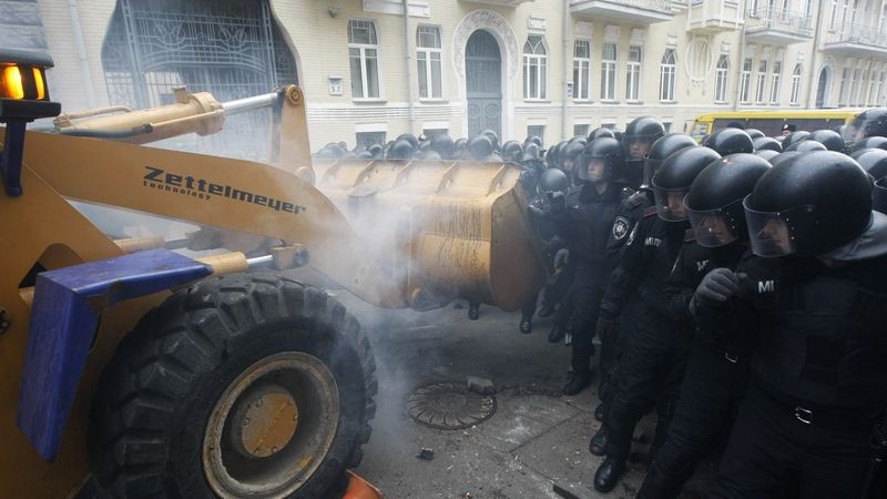 Protestující demonstranti použili k prolomení policejních zábran bagr. 