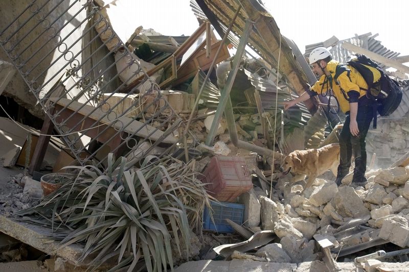 Záchranář prohlíží trosky domu v italské vesničce Onna, které postihlo zemětřesení.