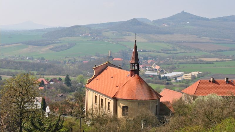 Pohled od Holého vrchu, válcovitá věž pod kostelem svatých Petra a Pavla patří Skalce ve Vlastislavi, na vrchu vpravo se tyčí Oltářík.