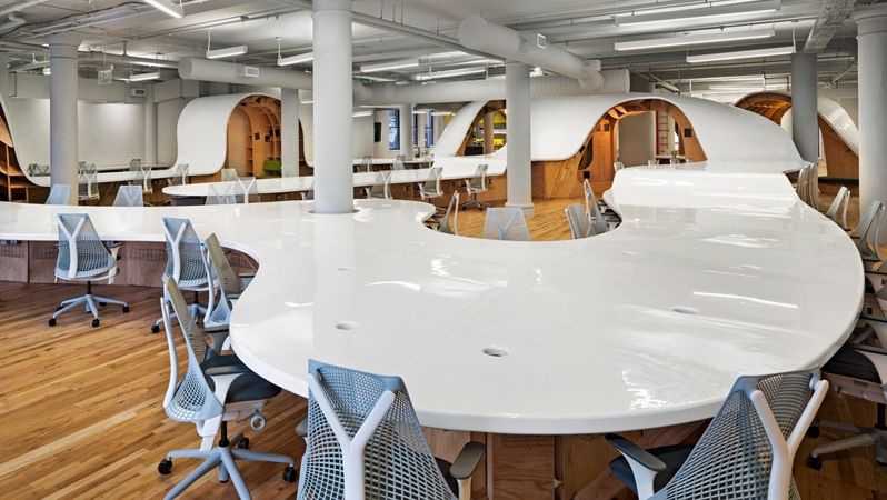 Designéři stolu využili i pro vznik knihoven a posezení pod zvlněnou částí.