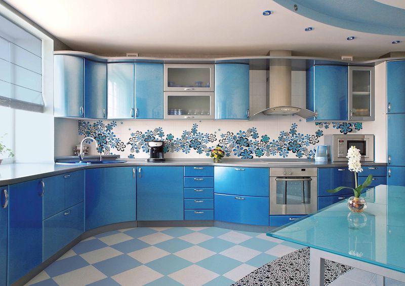 Celoskleněná stěna s květinami za kuchyňskou linku oživuje poklidnou, modrou atmosféru kuchyně.