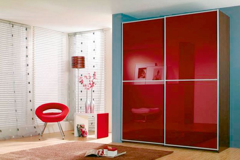 Moderní šatní skříň Linea v kombinaci ořech a červené sklo s posuvnými dveřmi, která je vybavena vnitřními policemi a šatními tyčemi.