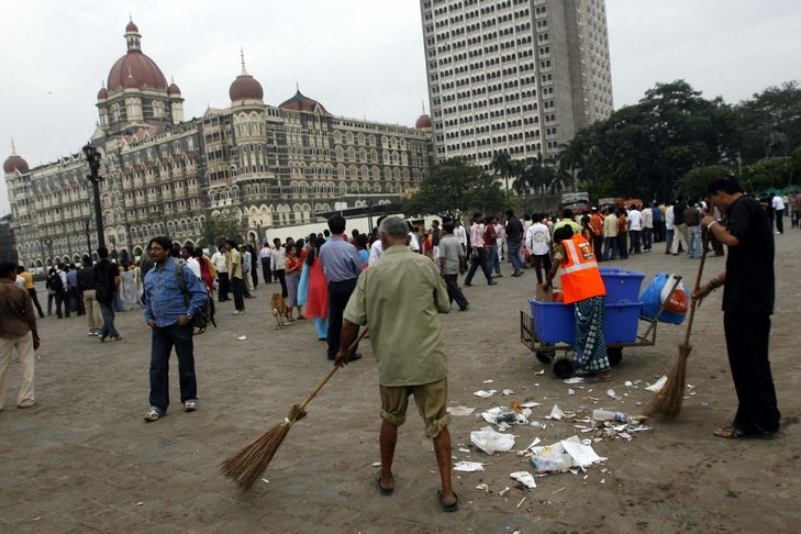 Metači uklízejí prostranství před hotelem Taj Mahal v Bombaji.