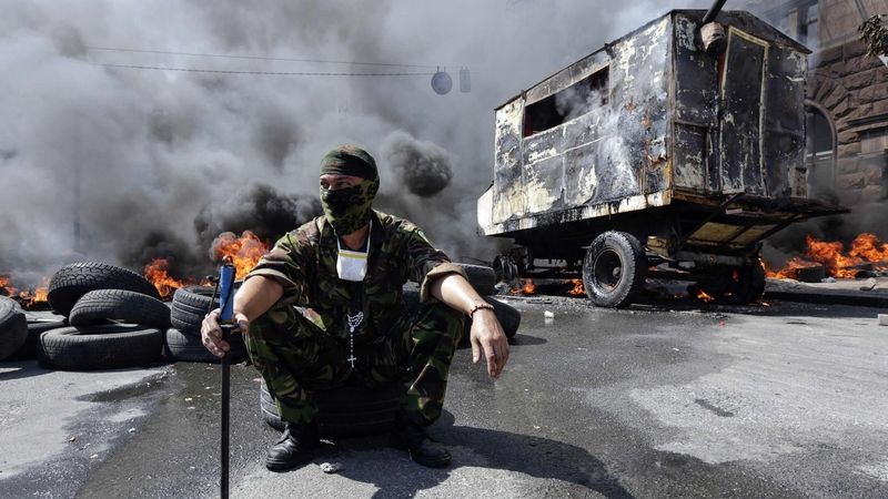 Demonstrant na kyjevském náměstí nezávislosti před zapálenou barikádou 