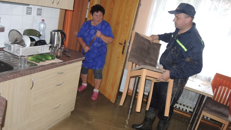 Dobrovolný hasič pomáhá vynášet věci ze zaplaveného domu v Šarovech u Zlína.