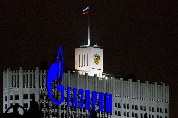 Logo ruského plynárenského gigantu Gazprom, v pozadí tzv. Bílý dům v Moskvě, sídlo vlády Ruské federace