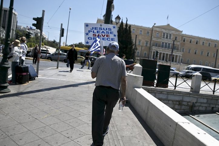 Ježíši, prosím zachraň Řecko, nese muž napsané na transparentu v Aténách