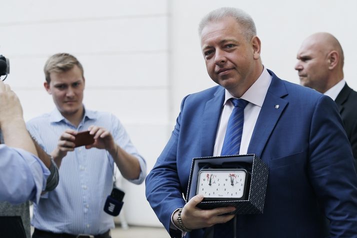 Ministr vnitra Milan Chovanec ukazuje šachové hodiny, které dostal na společné schůzce s prezidentem Milošem Zemanem také ministr financí Andrej Babiš a jež jsou nastaveny na za pět minut dvanáct.
