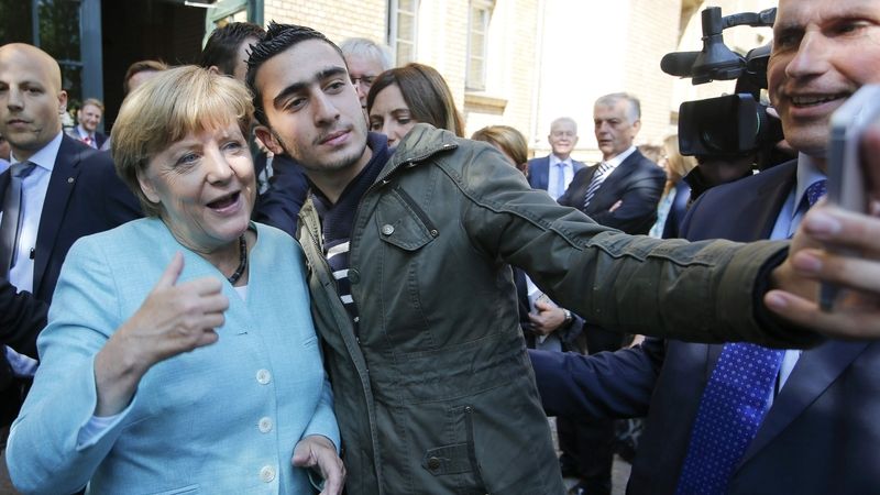 Uprchlík si dělá selfie s německou kancléřkou Angelou Merkelovou.