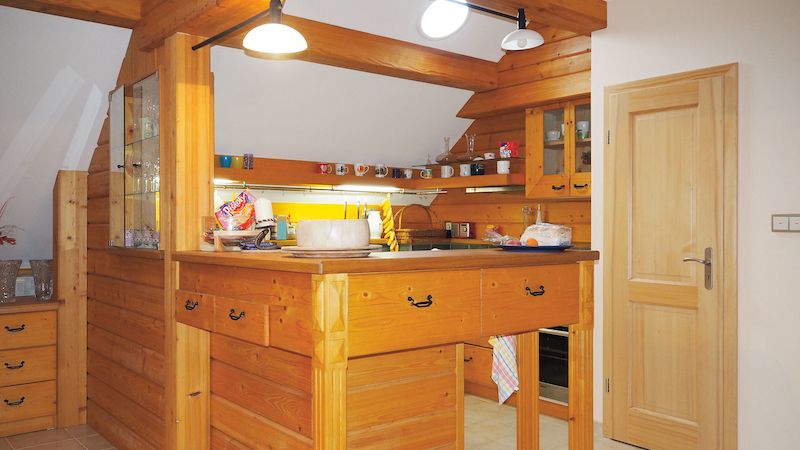 Dřevo má hlavní slovo v kuchyni, kde je také šikovně využit každý prostor i pod šikmými stropy.