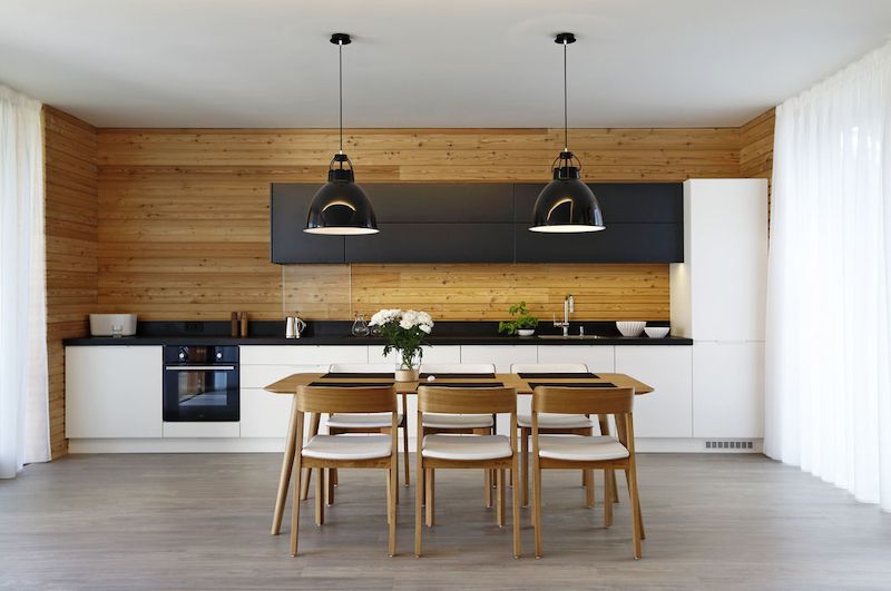 Obložení v exteriéru se prolíná i do interiéru, teplé modřínové dřevo je nedílnou součástí výrazu kuchyňské linky. Stůl a židle jsou od firmy TON.